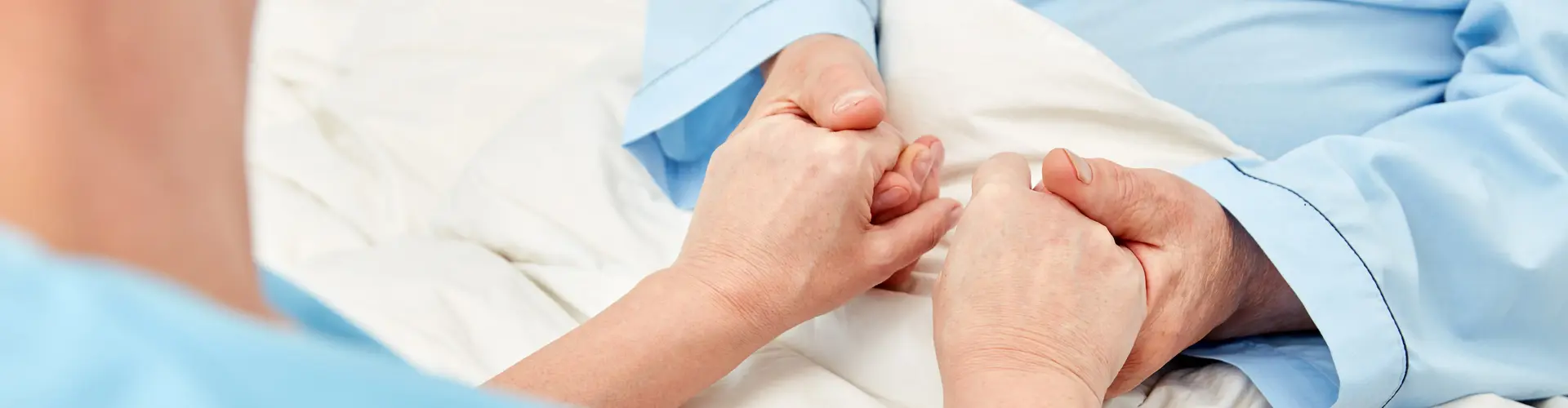 Pflegerin hält Hände eines Patienten